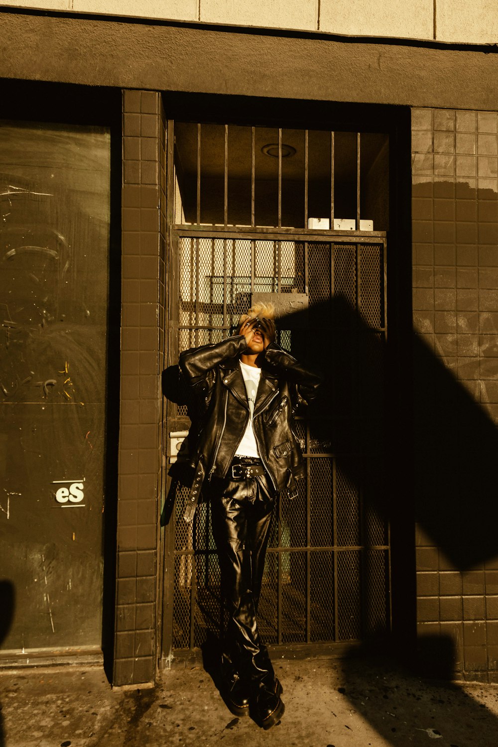 man in black jacket standing beside black wall