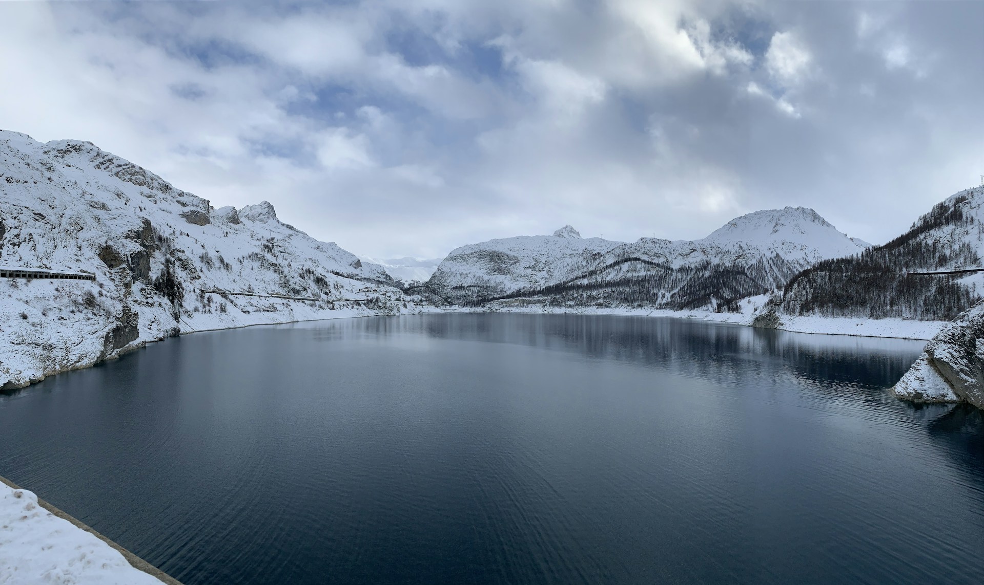 snow covered mountain beside body of water during daytime