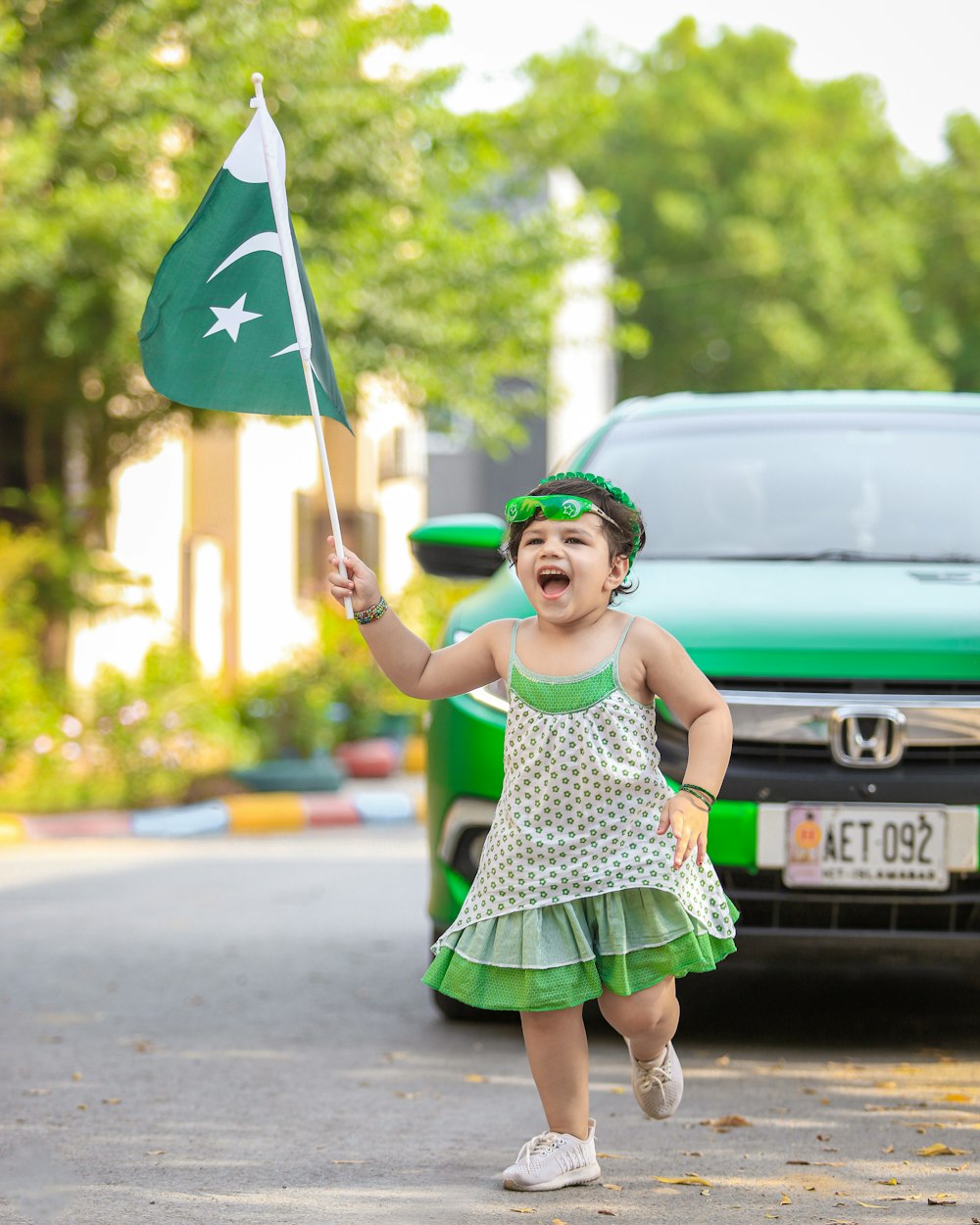 girl in green and white polka dot dress holding green and blue flag