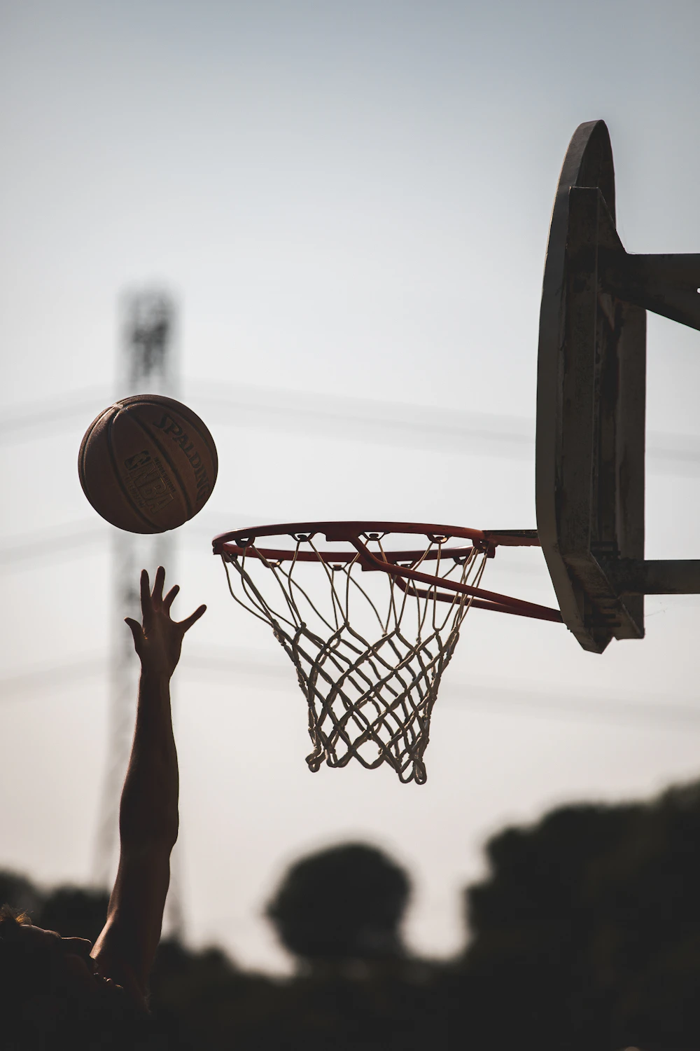 Silhouetted hand releasing a ball toward the rim
