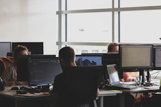 A diverse team of developers collaborating over laptops in a modern office space filled with natural light.