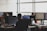 Several people working at desks with computer monitors, focusing on programming and other tasks. The office space is bright with natural light from large windows.