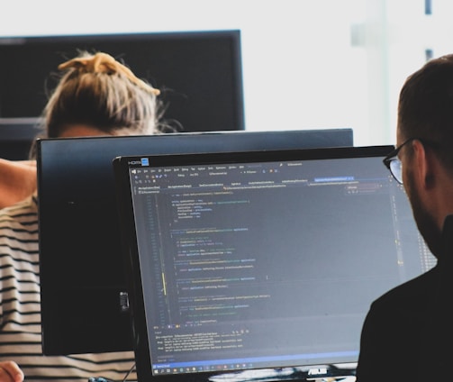 woman in black shirt sitting beside black flat screen computer monitor