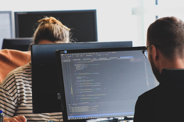 Office scene with two people focusing on coding tasks, demonstrating practical use of language model