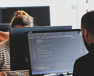 woman in black shirt sitting beside black flat screen computer monitor