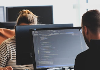 woman in black shirt sitting beside black flat screen computer monitor