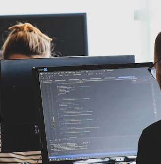 woman in black shirt sitting beside black flat screen computer monitor