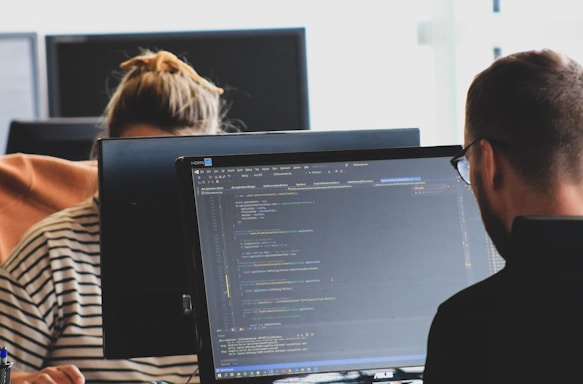 woman in black shirt sitting beside black flat screen computer monitor