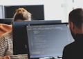 woman in black shirt sitting beside black flat screen computer monitor