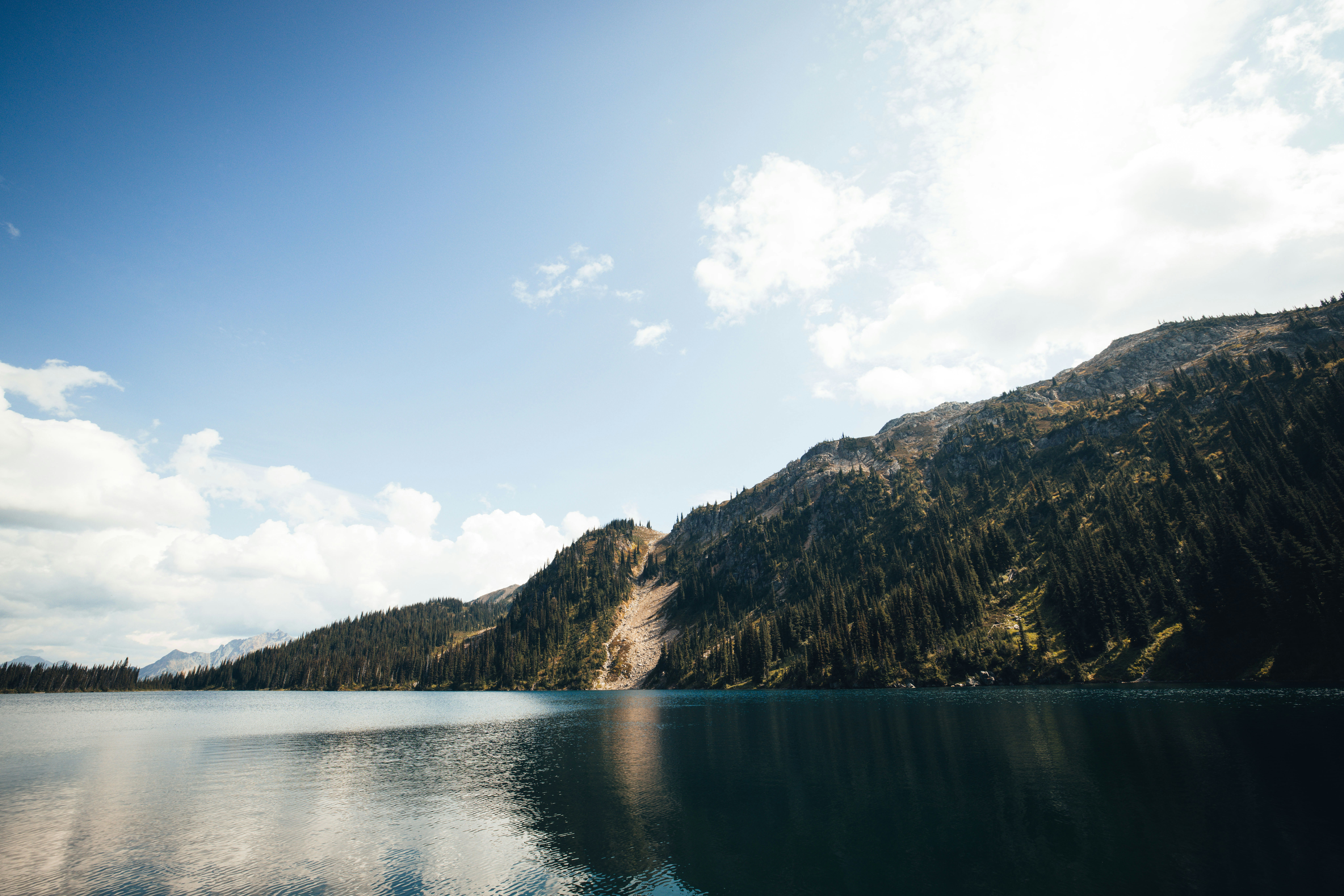lake surrounded by mountains under blue sky during daytime
