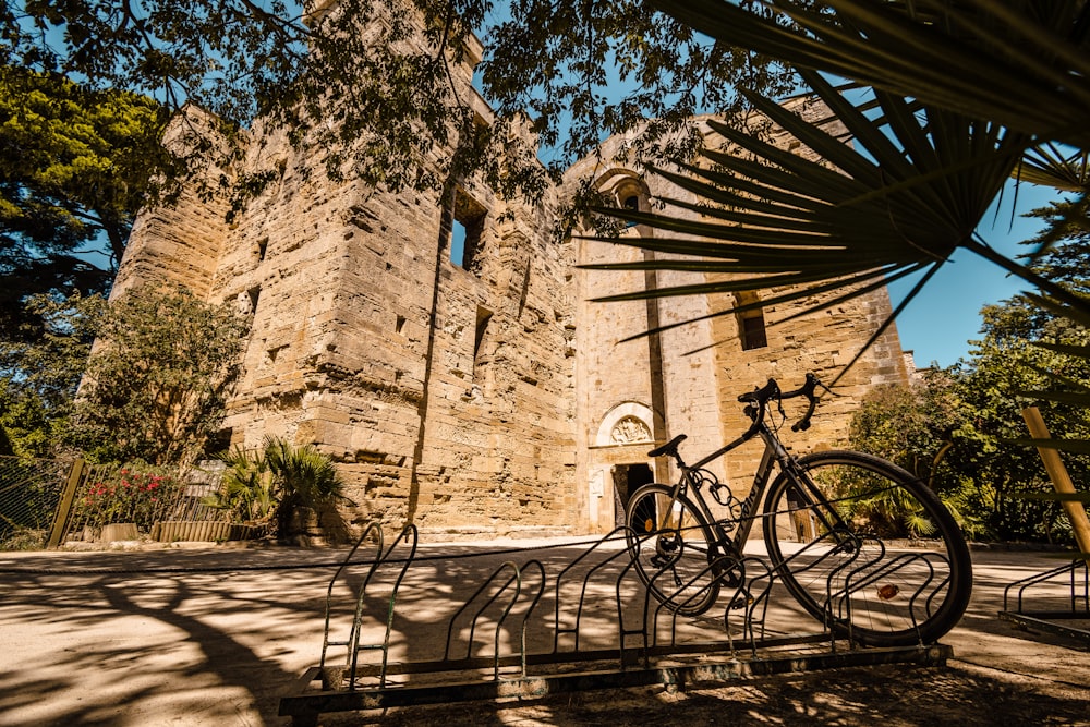 black bicycle parked beside brown concrete building during daytime