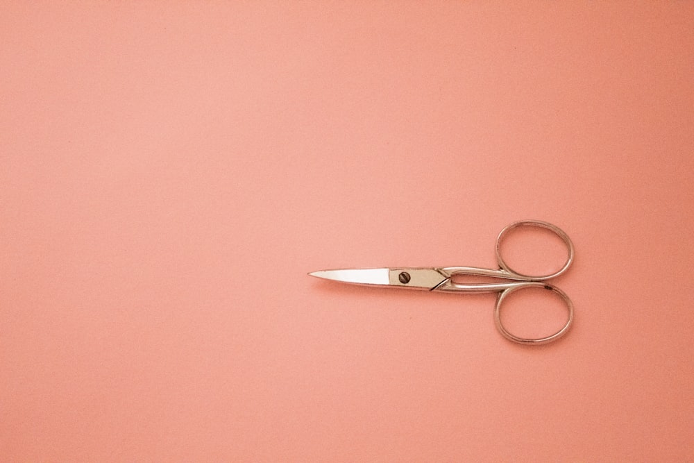 a pair of rose gold scissors on a flat pink surface