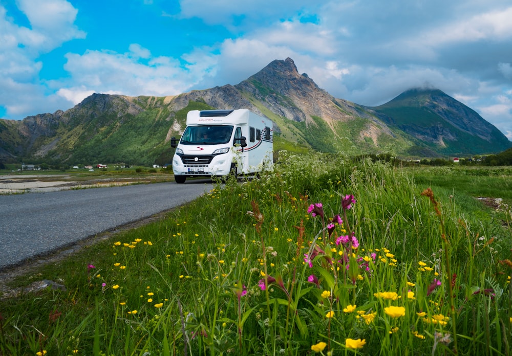 white van on road near green grass field and mountain during daytime