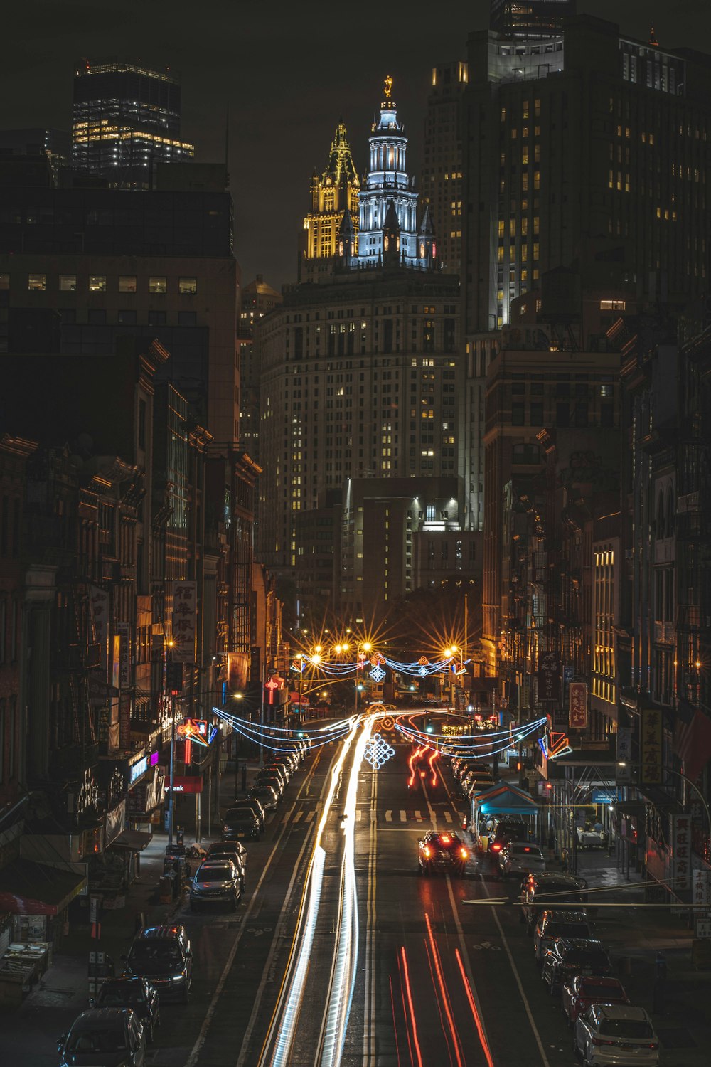 cars on road between high rise buildings during night time