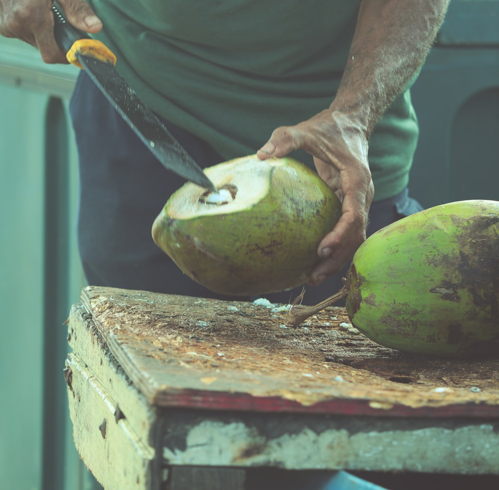 person in gray t-shirt holding green fruit