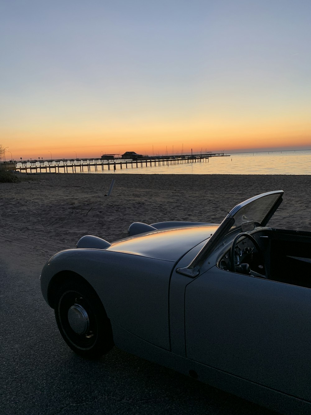 black convertible car on gray sand during sunset
