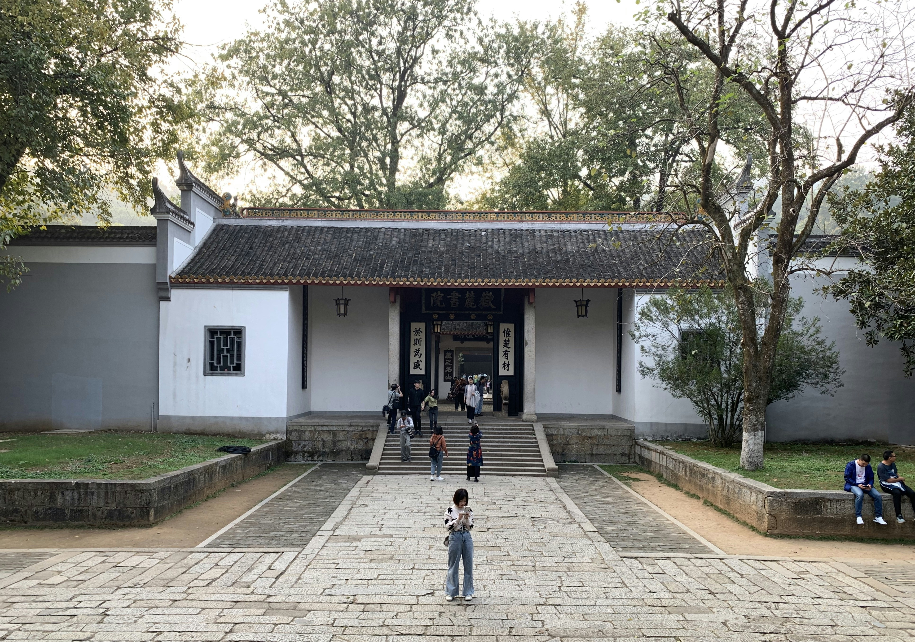 person in black jacket walking on sidewalk near white and brown house during daytime