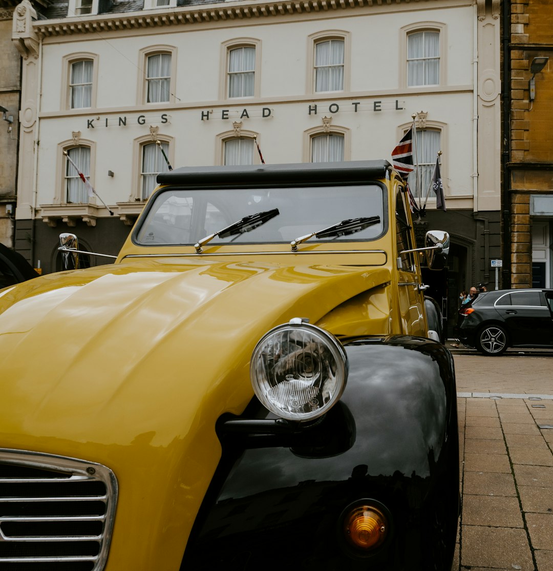 yellow and black vintage car parked beside white concrete building during daytime