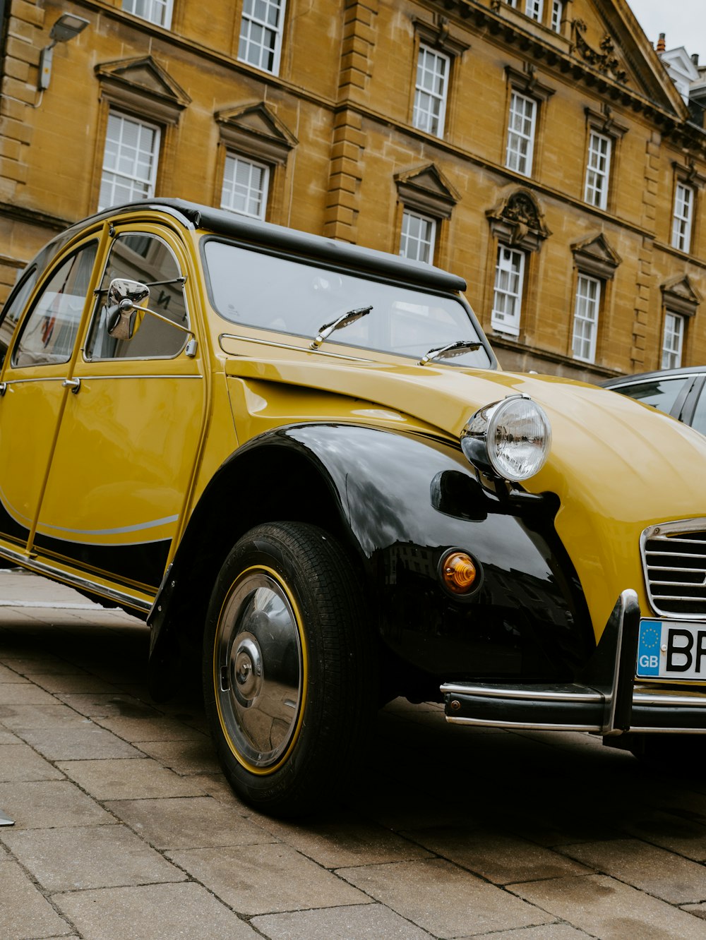 yellow and black vintage car parked on sidewalk during daytime