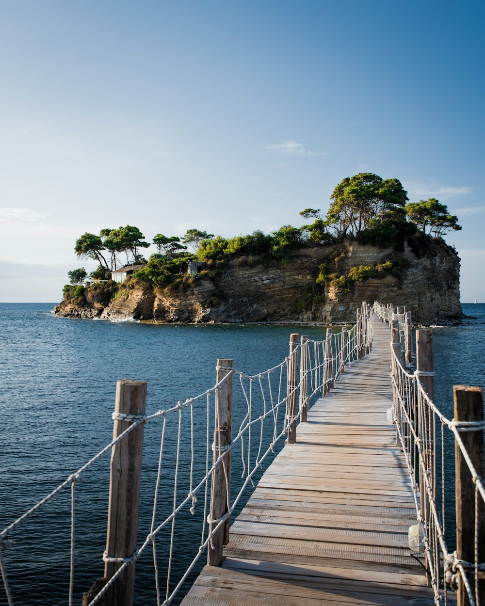 brown wooden bridge over blue sea under blue sky during daytime