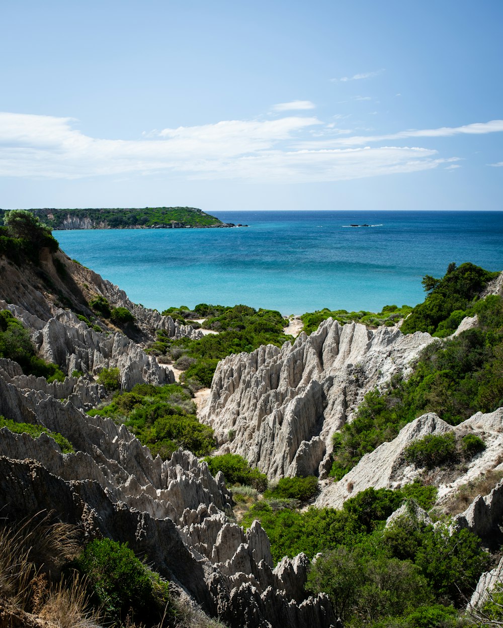 gray rocky mountain beside blue sea under blue sky during daytime