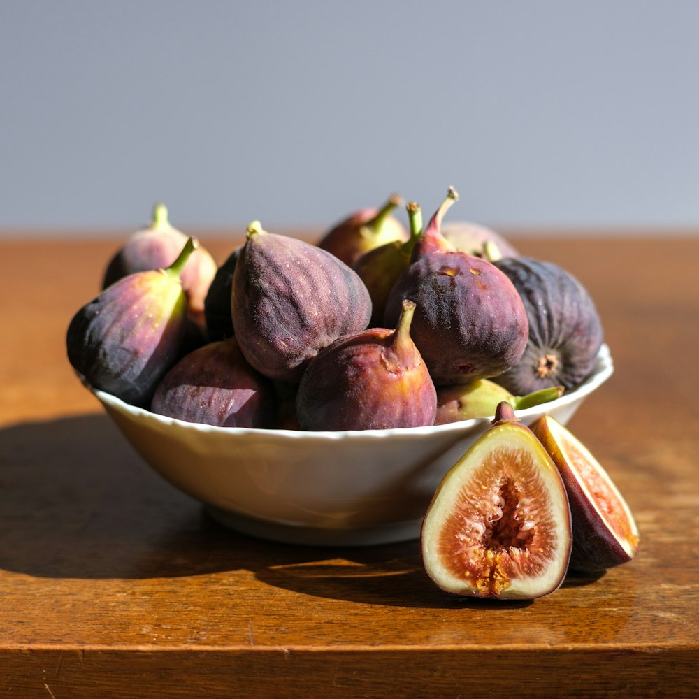 purple and brown fruit on brown ceramic bowl