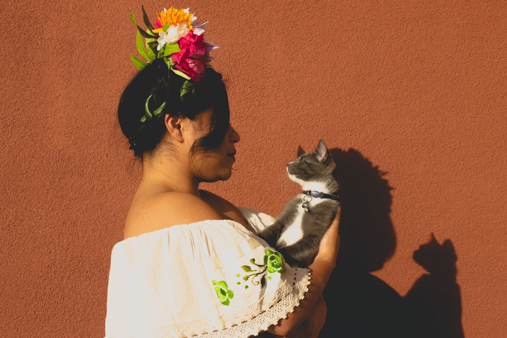 woman in white floral dress carrying black and white cat