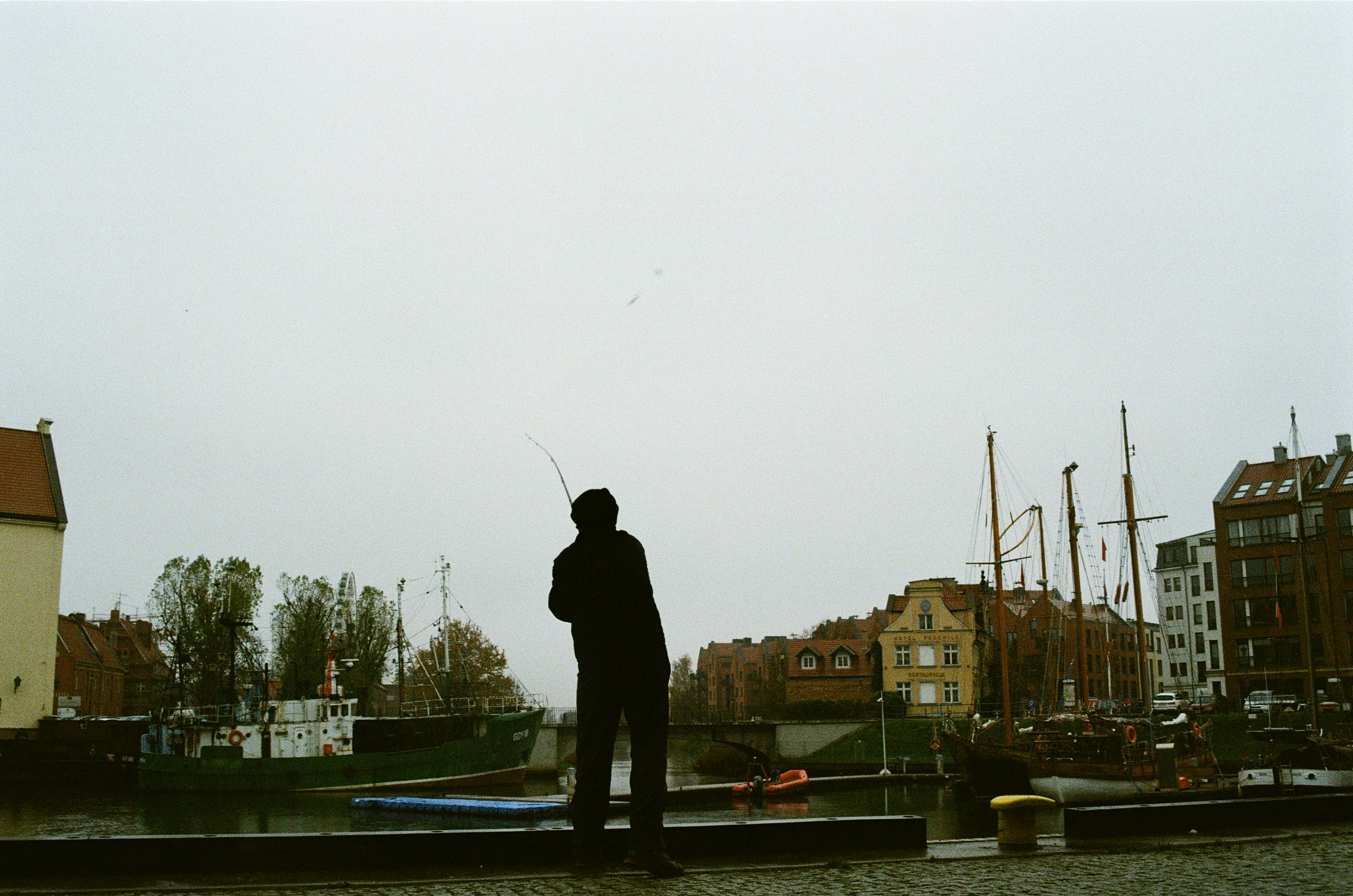man in black jacket and pants standing on bridge during daytime