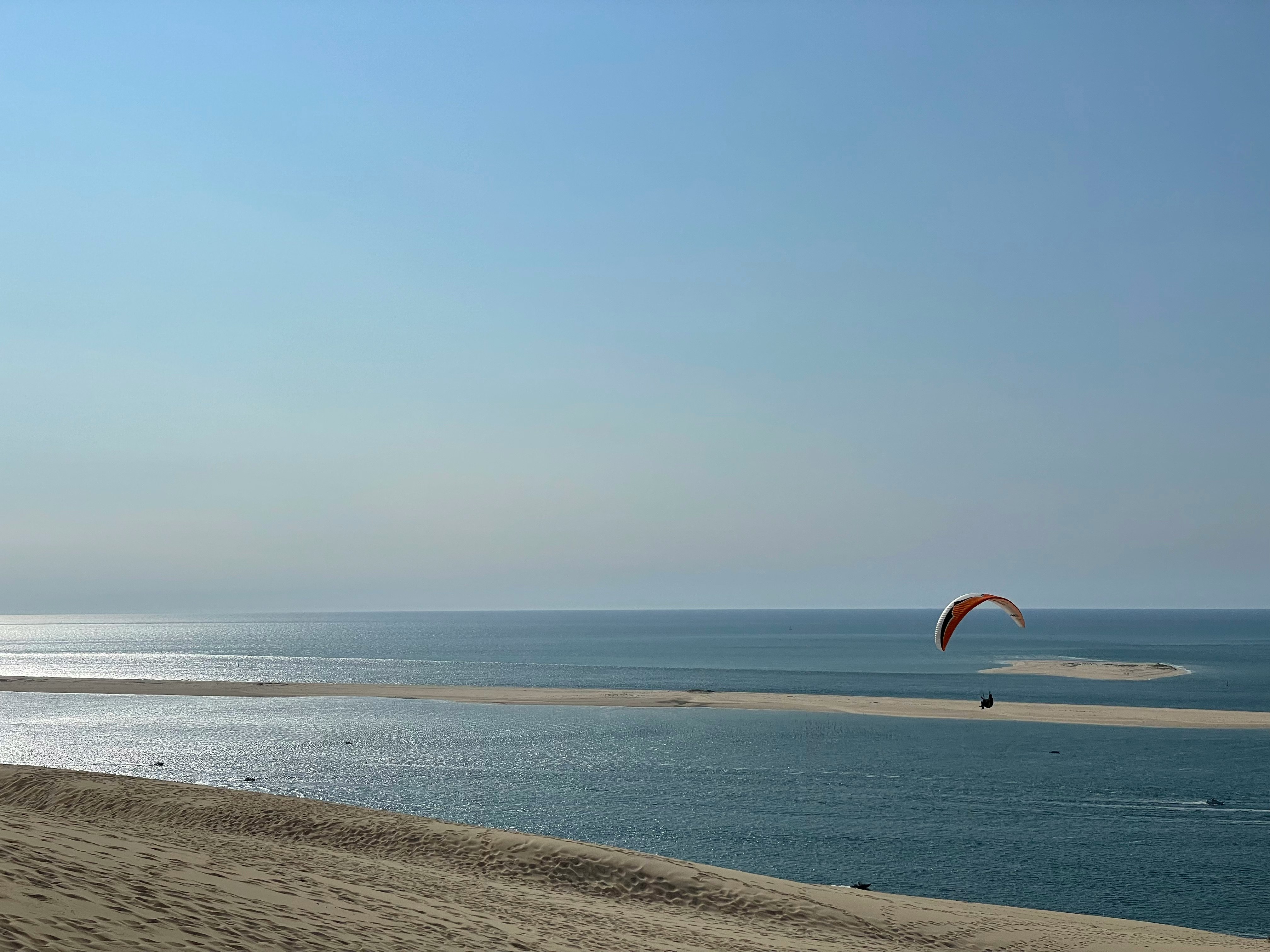 person in orange and yellow parachute over the sea during daytime