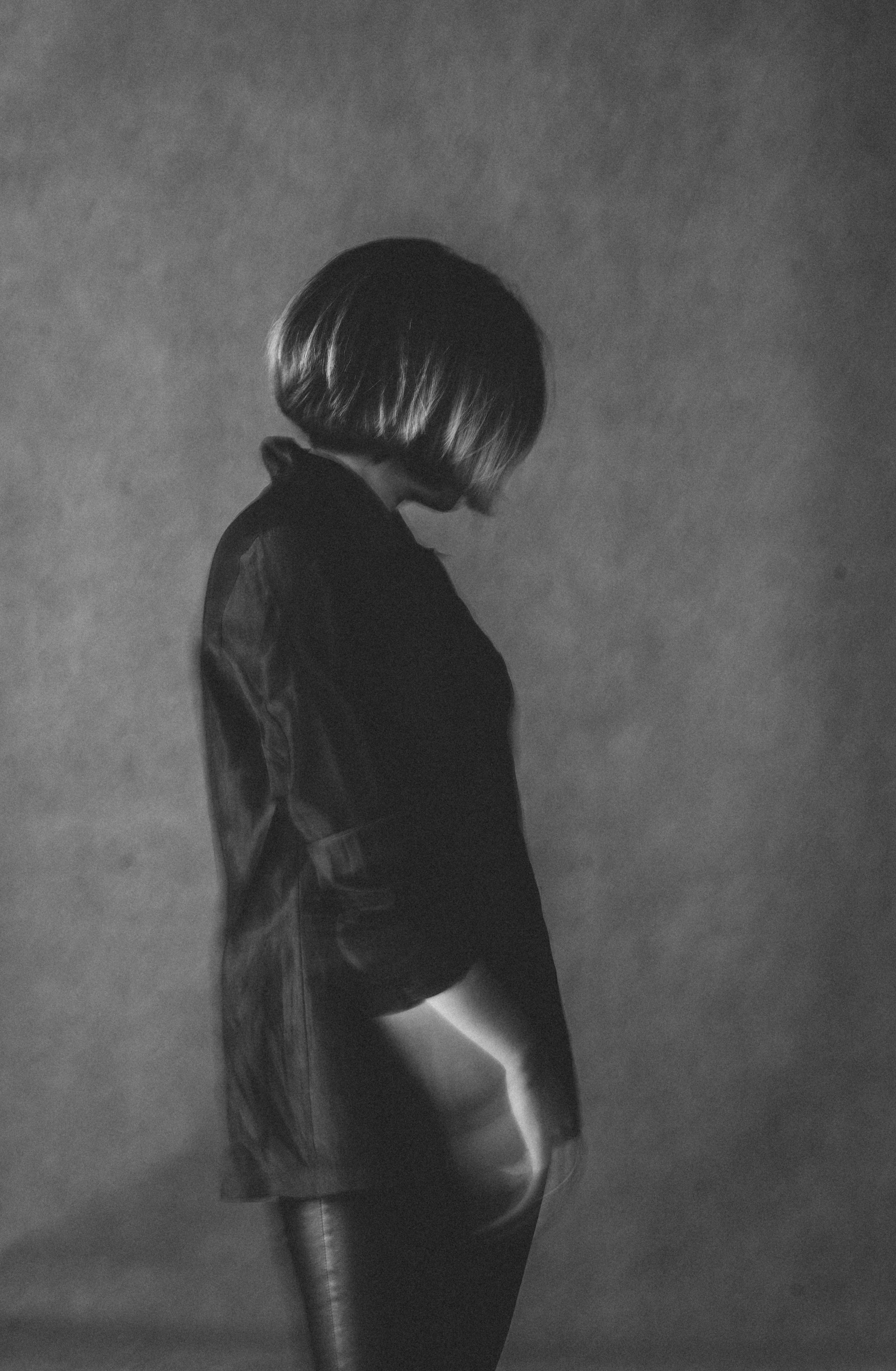 Black and white photo of a client with sleek, textured hair styled in a 90's-inspired glam look, captured in a minimalist studio setting.