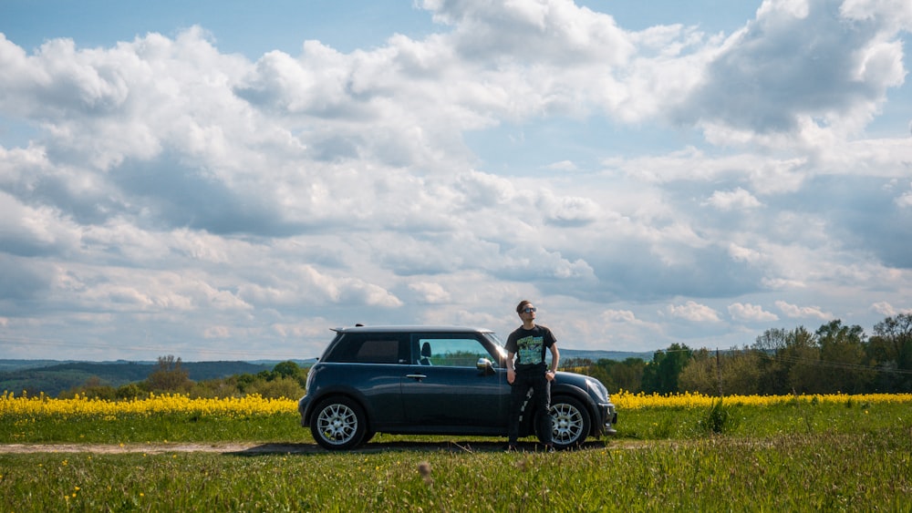 man in black jacket standing beside black suv during daytime