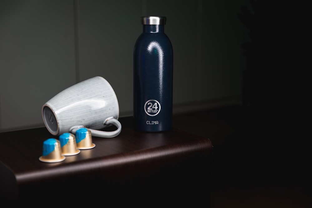 blue and white plastic bottle beside white ceramic mug