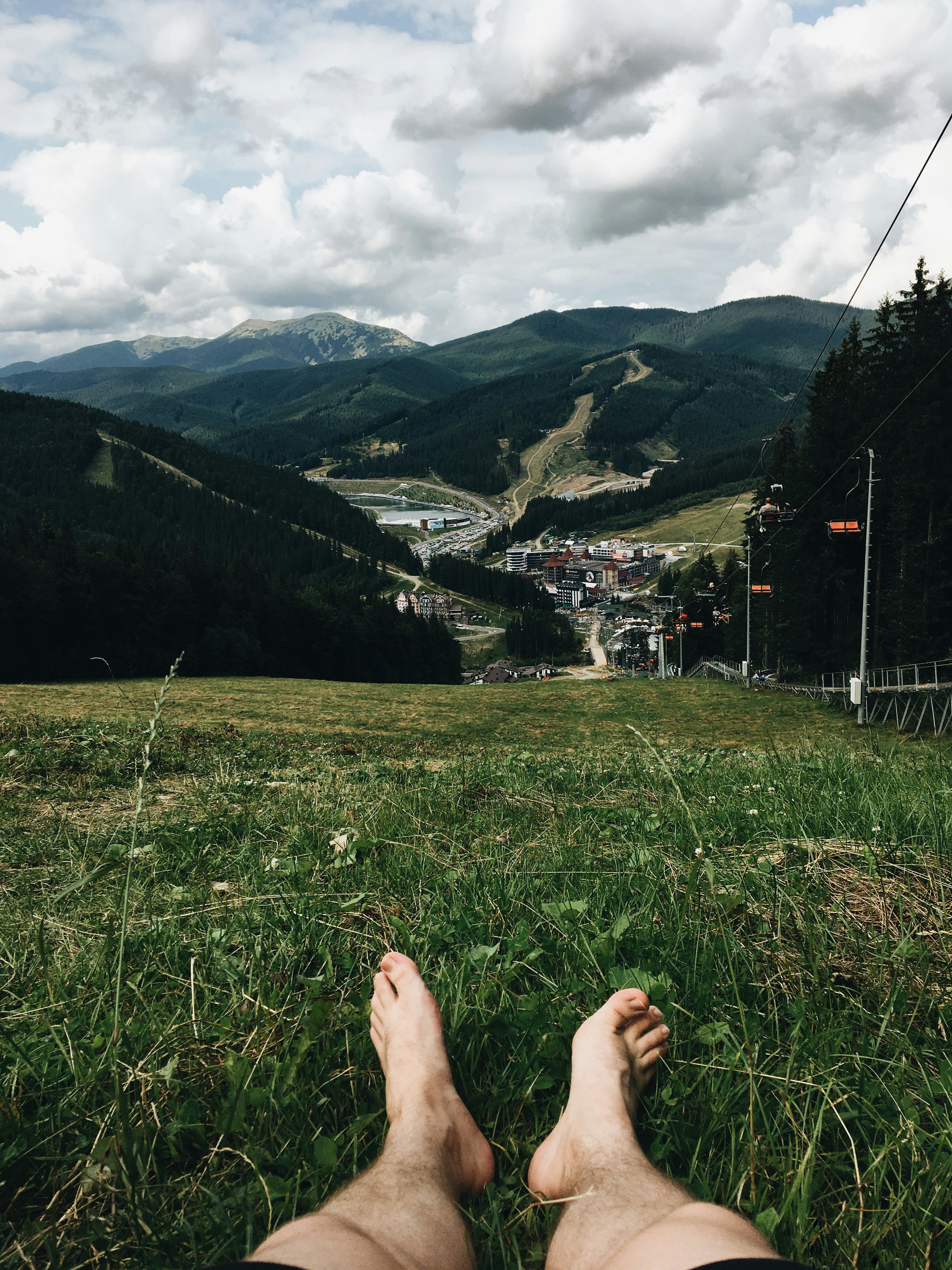 person sitting on grass field near mountain during daytime