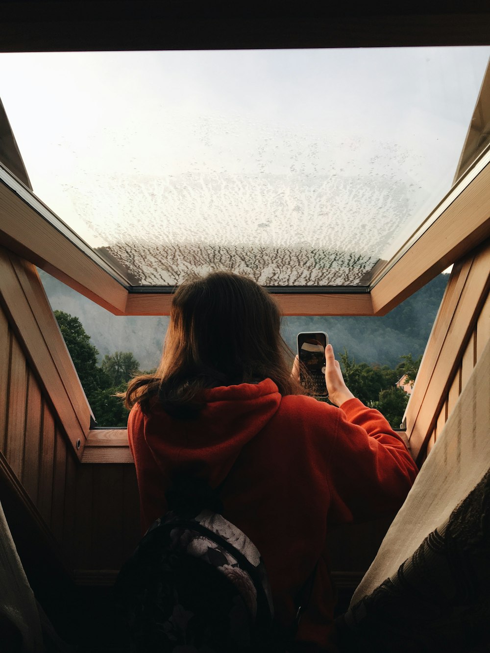 woman in red hoodie taking photo of snow covered ground