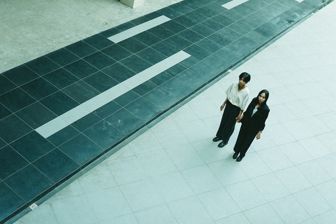 man in black suit jacket and black pants walking on white floor tiles