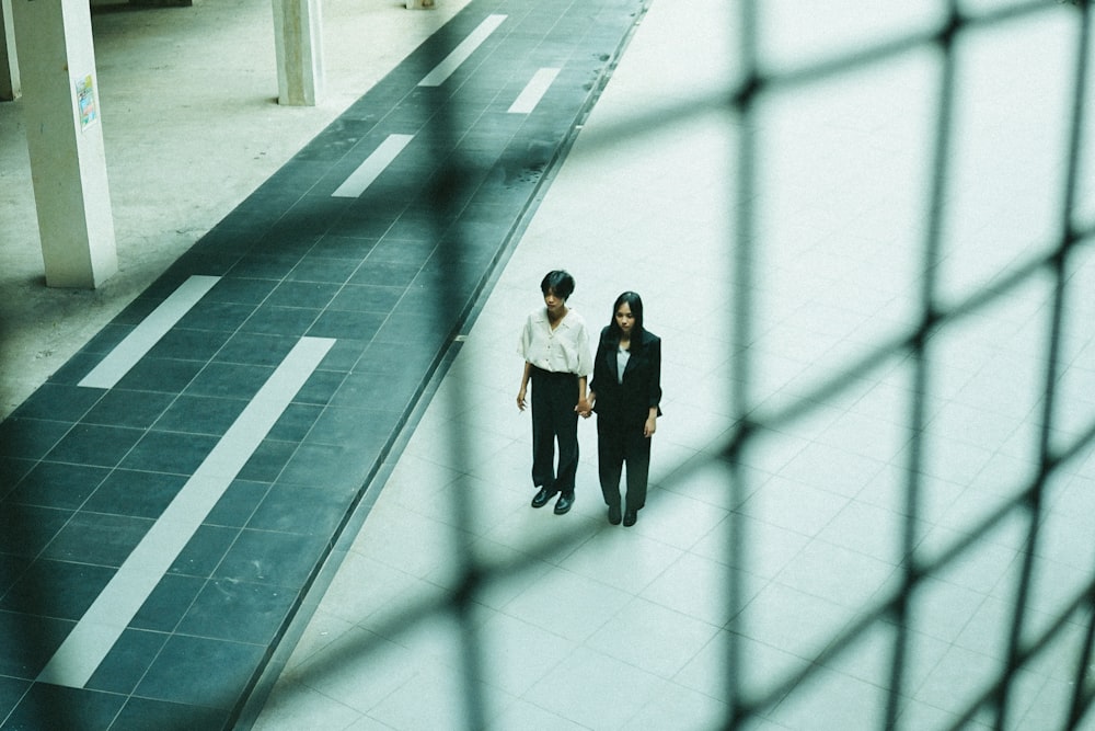 man in white shirt and black pants standing on white floor tiles