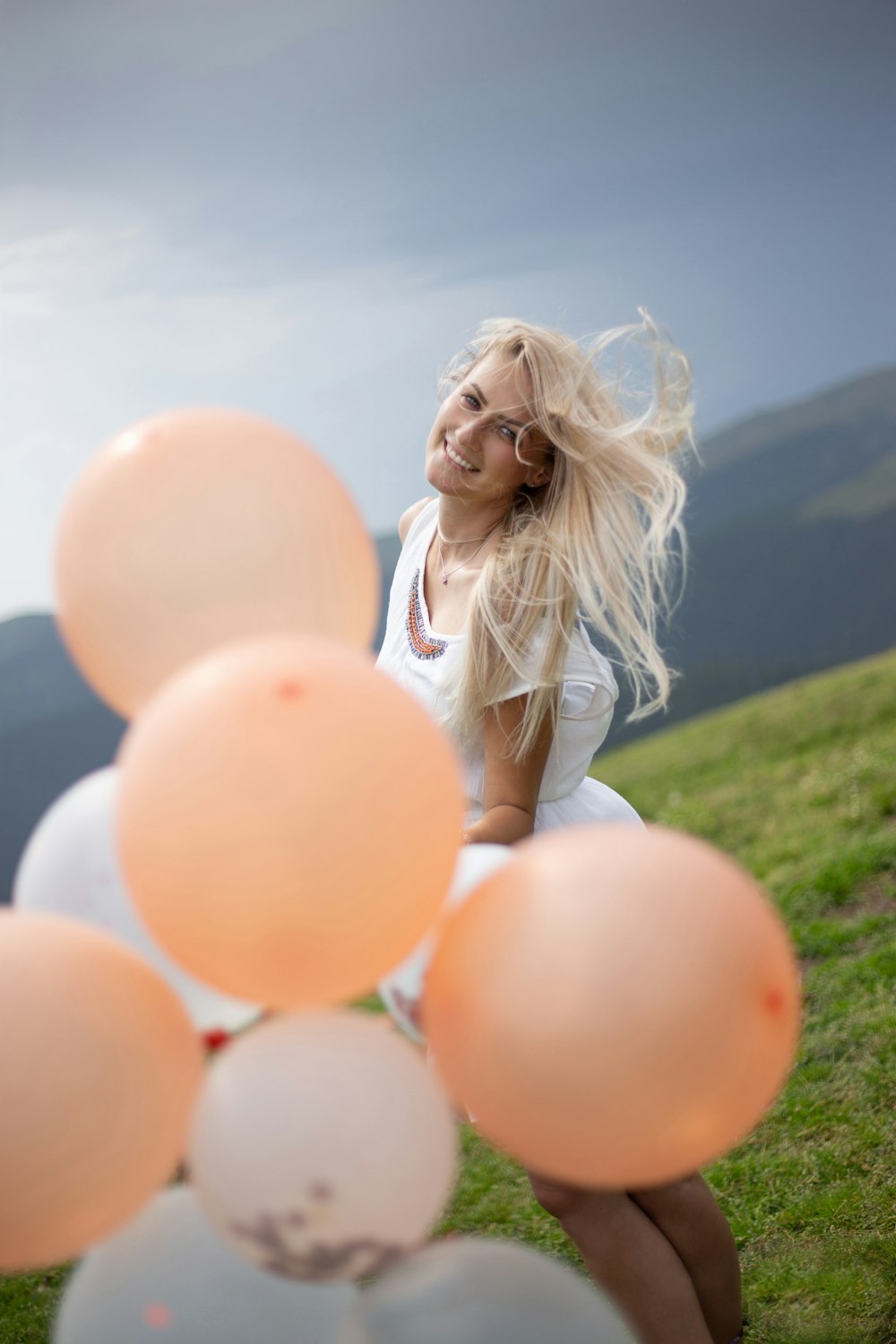 girl in white dress holding balloons on green grass field during daytime