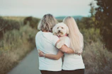 woman in blue t-shirt hugging white dog