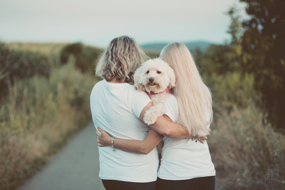 woman in blue t-shirt hugging white dog