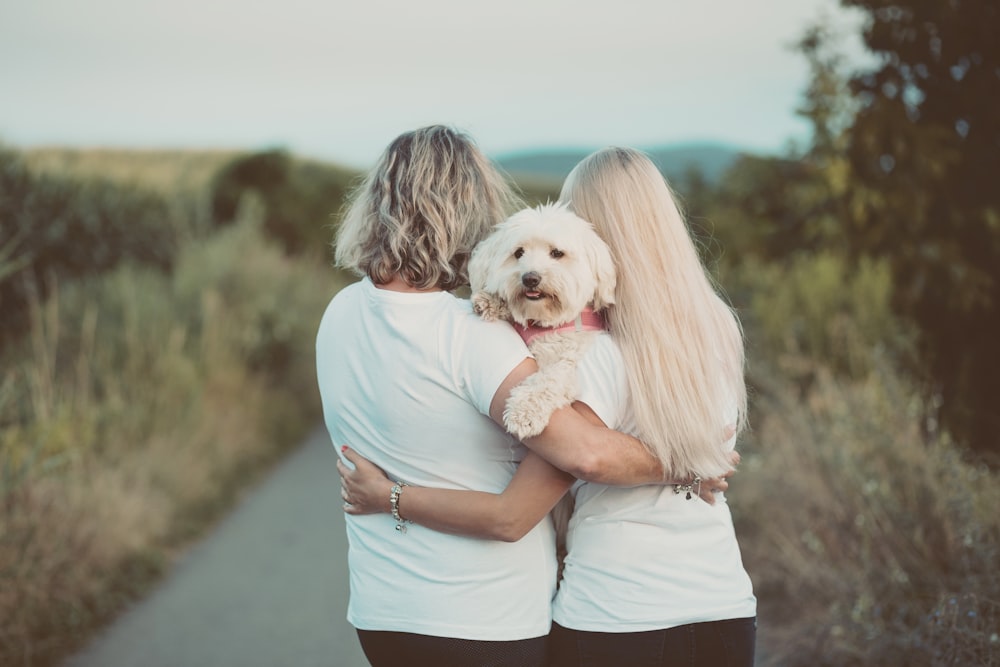 Frau im blauen T-Shirt umarmt weißen Hund