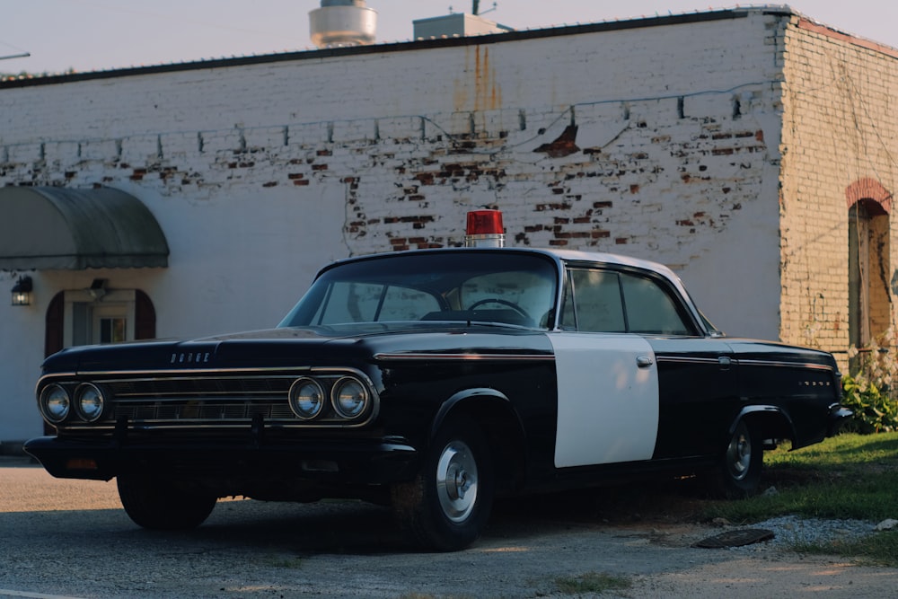 black and white classic car parked beside white concrete building during daytime