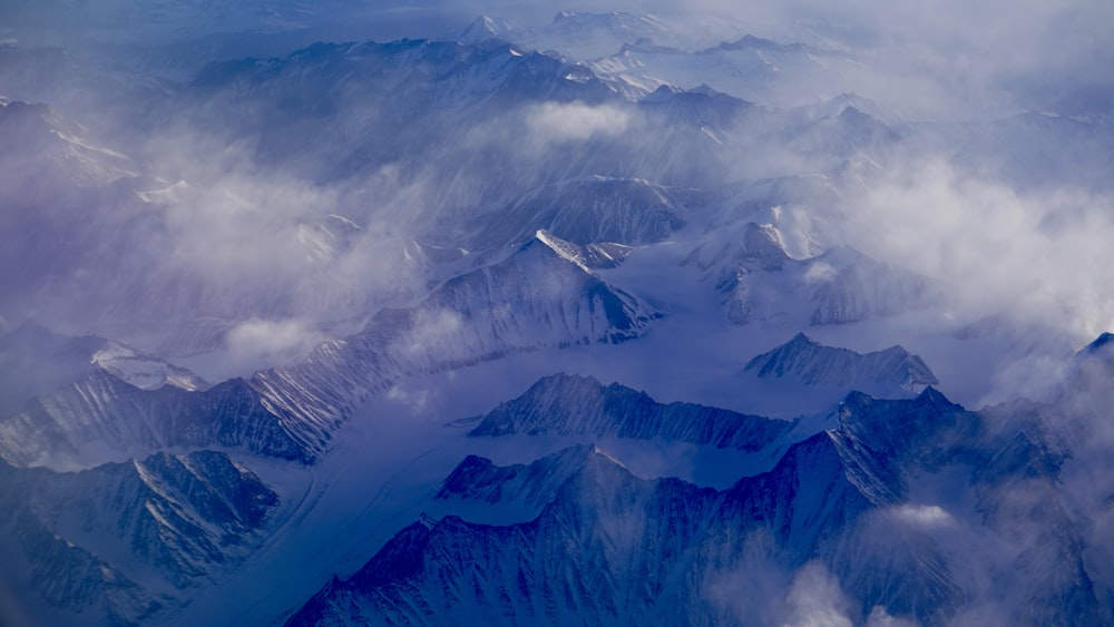 snow covered mountain under white clouds during daytime