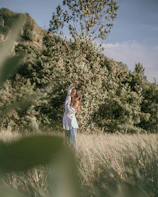 A woman standing in a sunlit field with golden light highlighting her confident posture.