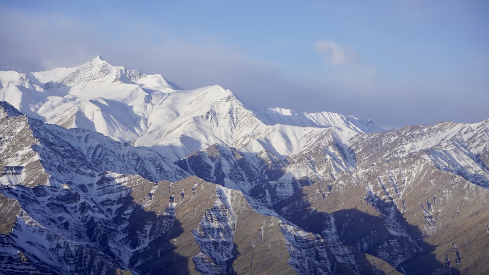 a mountain range covered in snow under a blue sky