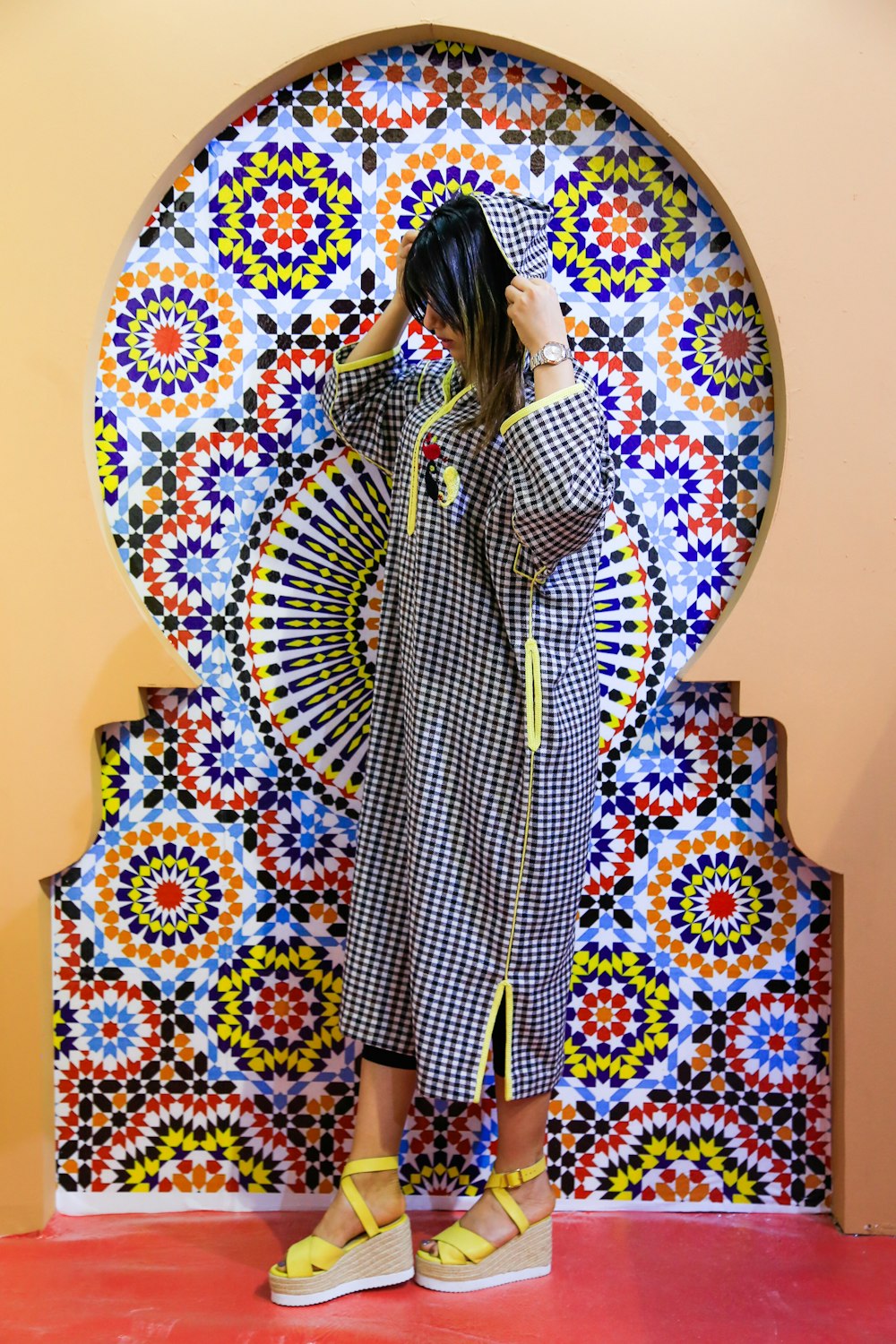 woman in white and black long sleeve dress standing beside round white and brown floral wall