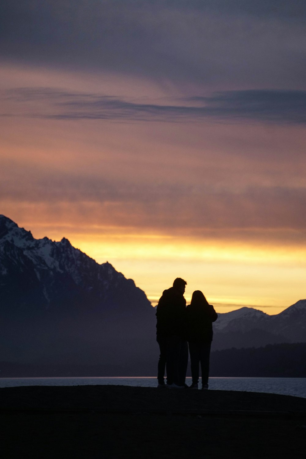 silhouette of 2 person standing on mountain during sunset