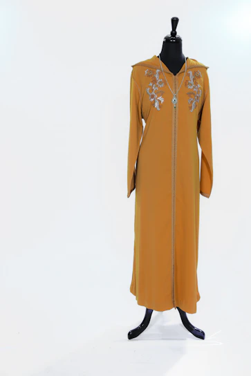 A beautifully embroidered traditional Moroccan caftan displayed on a mannequin in a sunlit boutique.