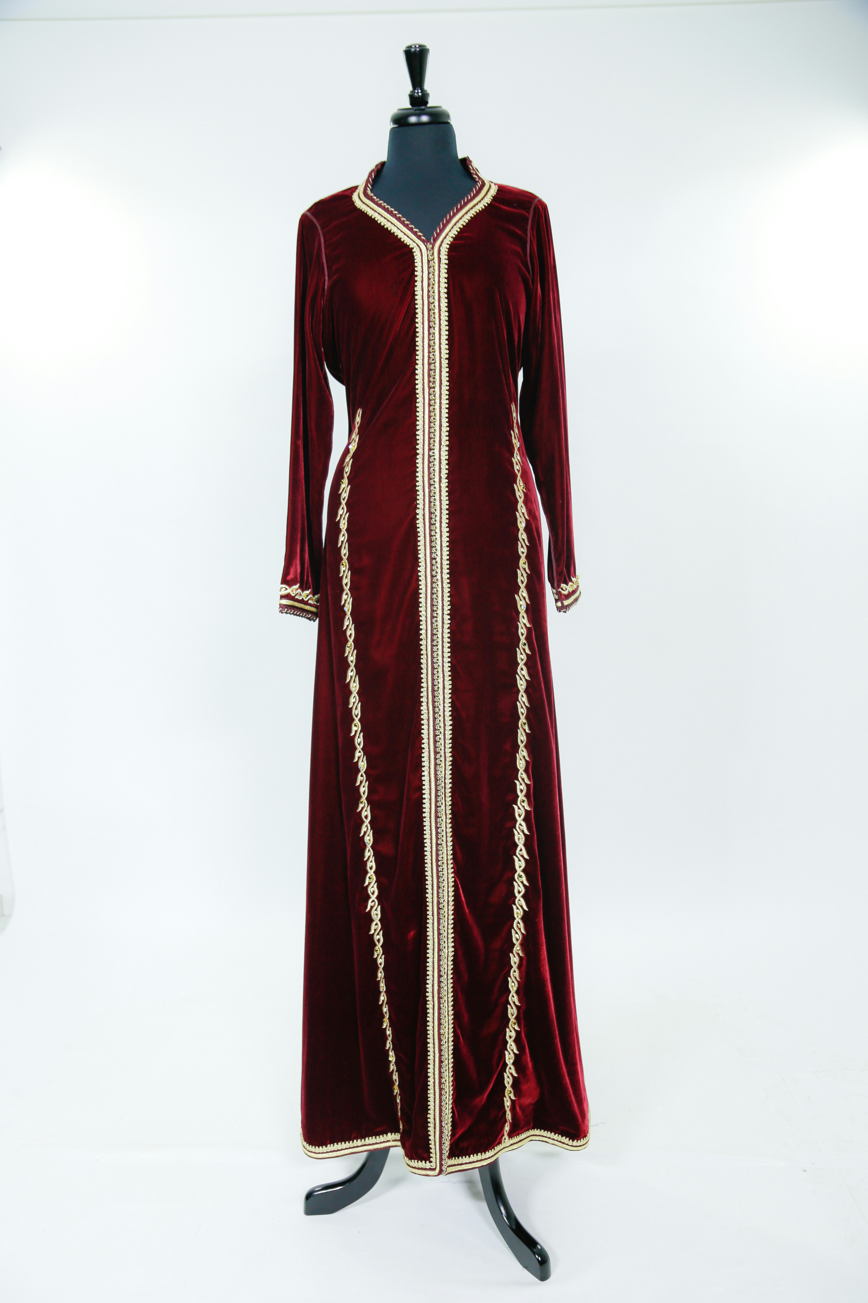 Rose-toned abaya with intricate gold embroidery at cuffs, warm studio lighting