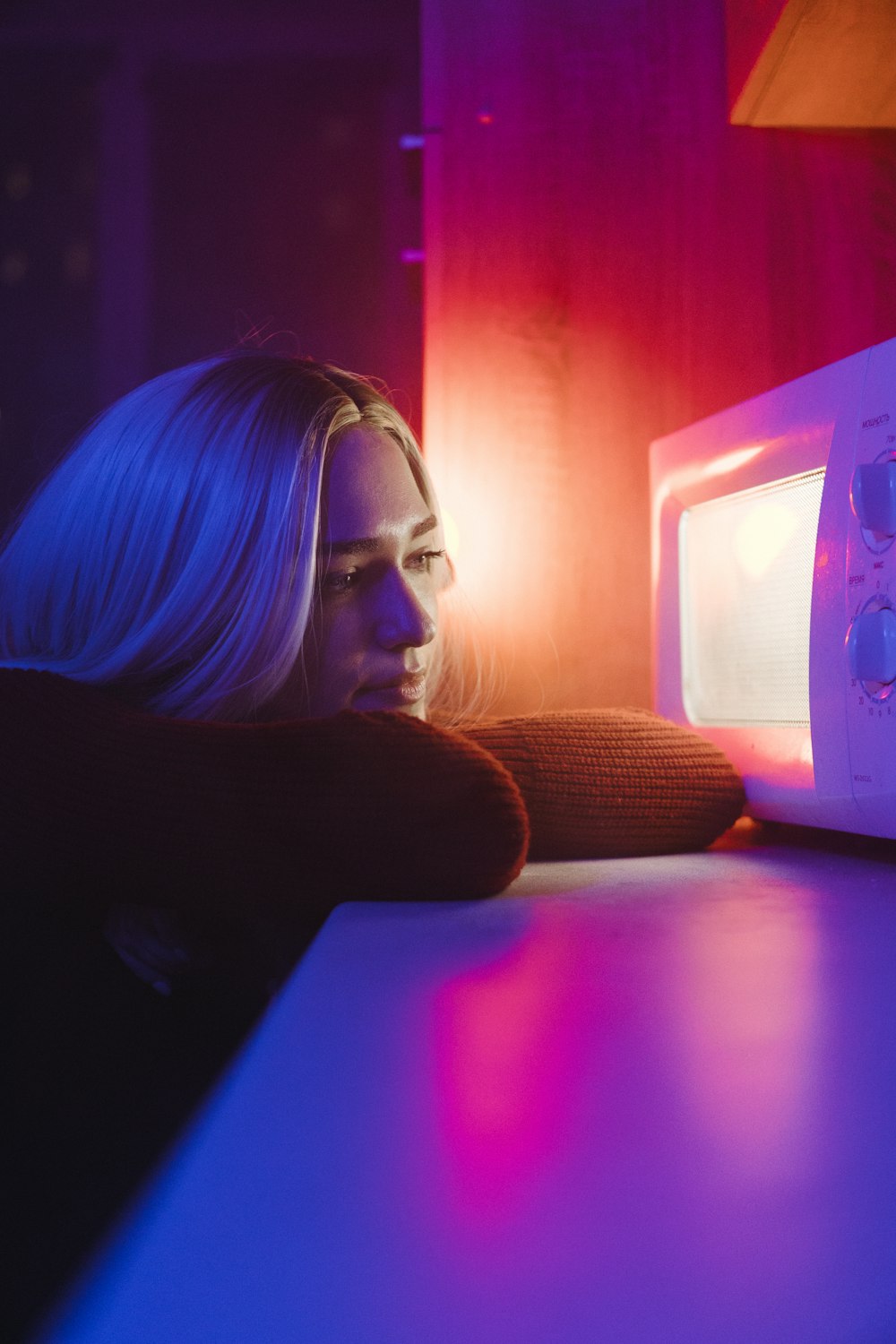 Femme en chemise noire à manches longues assise à côté d’un four à micro-ondes blanc