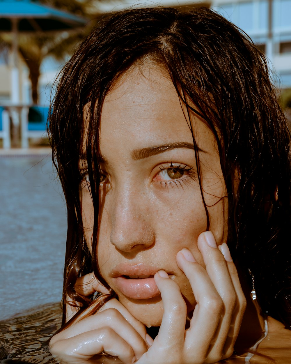 woman in white and black stripe shirt covering her face with her hand